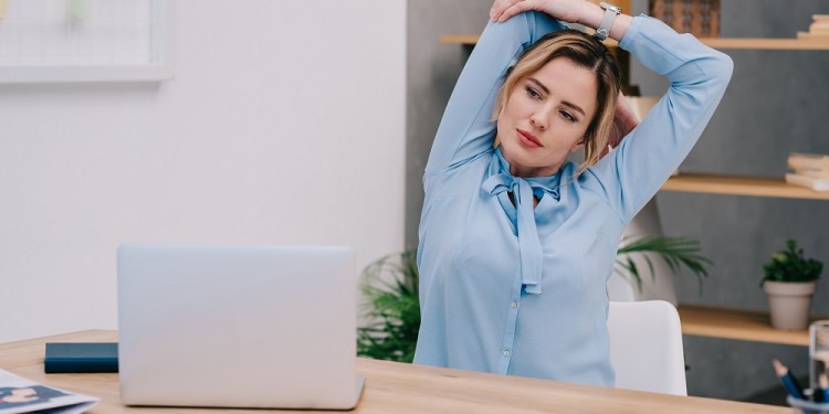 businesswoman stretching shoulders at workplace in office
