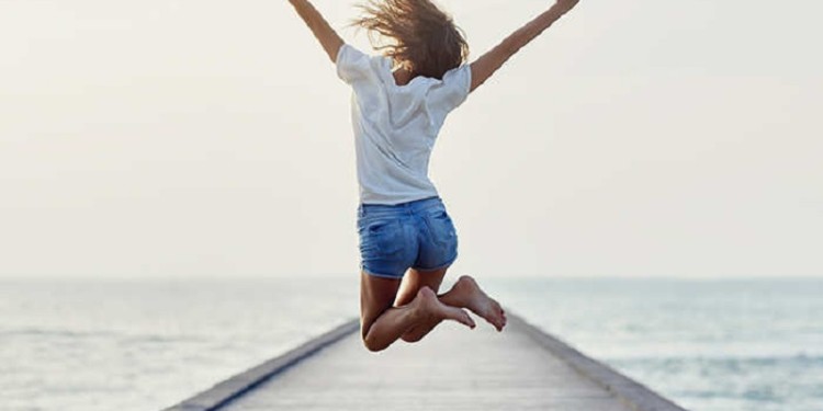 Back view of jumping girl on the pier. Freedom concept
