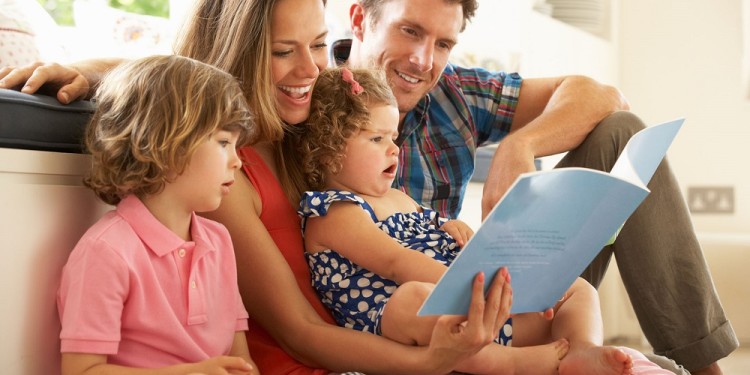 Parents Sitting On Floor With Children Reading Story Indoors Together