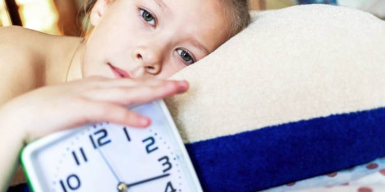 Girl sleeping on a pillow with an alarm clock in hand resting in the morning