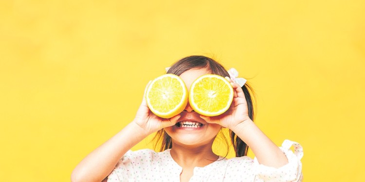 Little girl child covering eyes with orange.