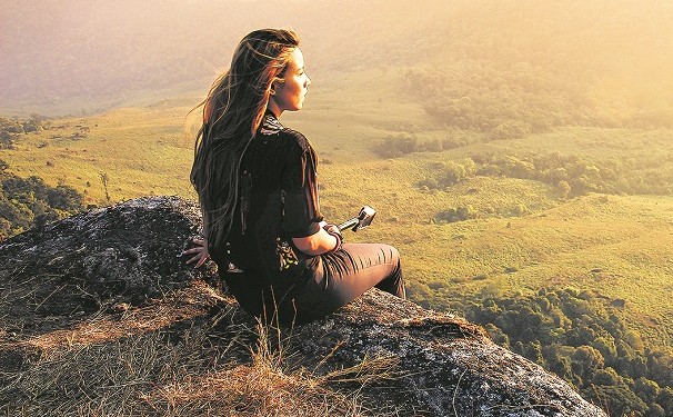 Hipster young girl with backpack enjoying sunset on peak of foggy mountain. Tourist traveler on background view mockup. Hiker looking sunlight in trip in Thailand country. Vintage filtered image.