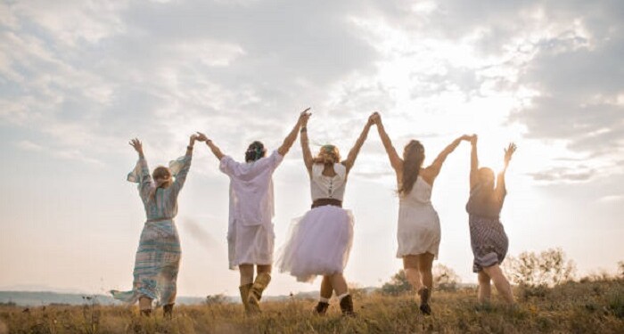 Group of happy female friends running on meadow.