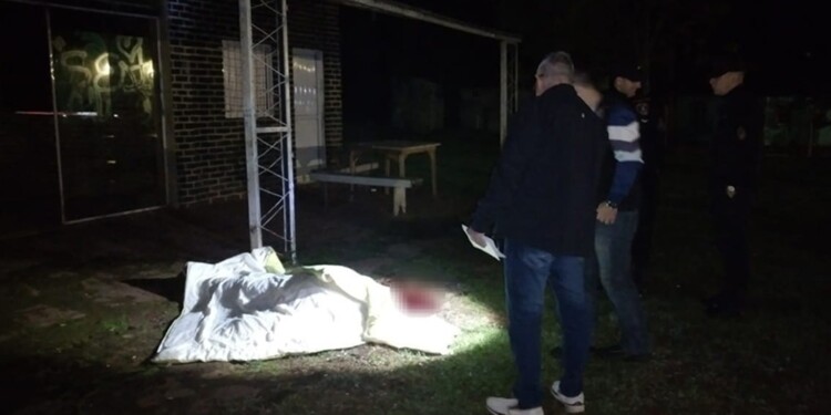 ESCENA. Ayala, en el suelo bajo una cobija y ya sin vida en la entrada del bar “El Momento” del Paraje 9 de Julio.