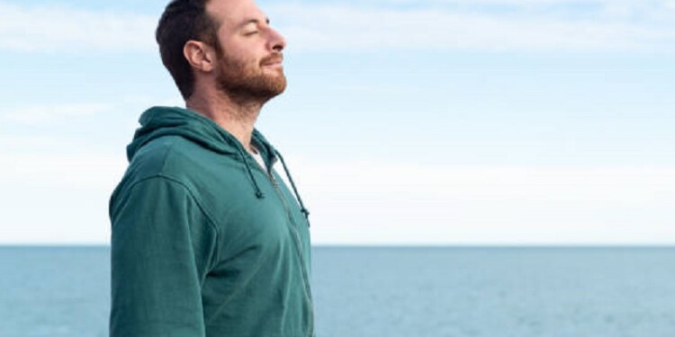 Relaxed man breathing fresh air with the sea at the background.