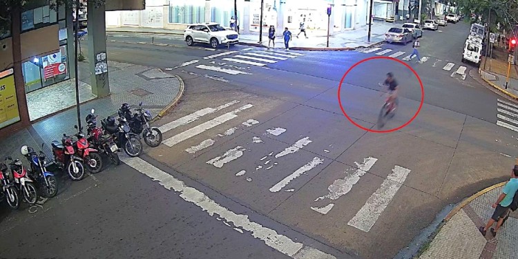 INSTANTE. El presunto ladrón en bicicleta a punto de cruzar la senda peatonal y finalizar su fuga contra un Peugeot 508 estacionado.