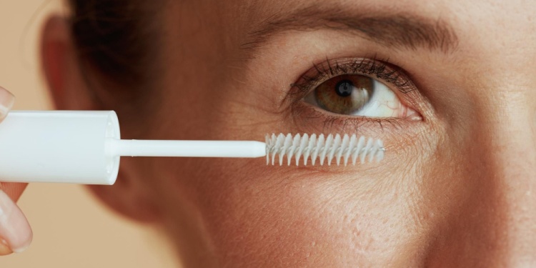 Closeup on modern female with lash gel mascara against beige background.
