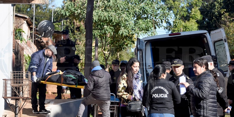 CONMOCIÓN. Efectivos sacan a una de las víctimas fatales del interior de la vivienda donde fue cometida la masacre.