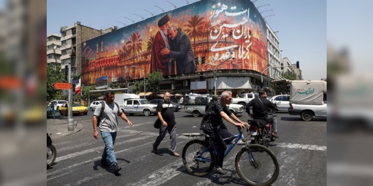 CONFLICTO. Varias personas pasan junto a una valla publicitaria con una imagen que muestra al difunto líder supremo de Irán, el ayatollah Ali Jamenei.