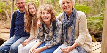 Grandparents and teens sitting on a bridge in a forest