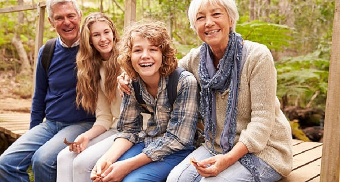 Grandparents and teens sitting on a bridge in a forest